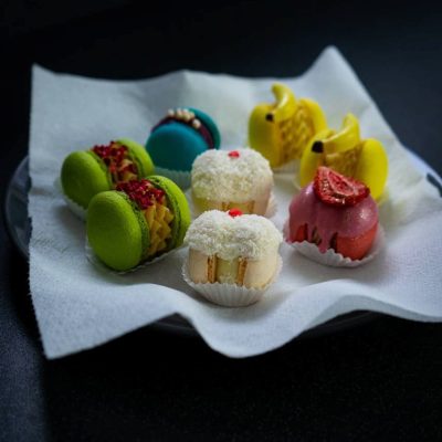 Assorted macarons on a plate, featuring vibrant colours and unique decorations.